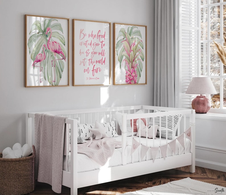 May include: Three framed prints with a tropical theme. The prints feature pink flamingos, green monstera leaves, and a pink pineapple. The center print has a pink quote that reads 'Be who God created you to be & you will set the world on fire.' The quote is attributed to St. Catherine of Siena.