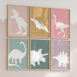 Adorable dinosaur art prints designed for a little girls room, featuring playful dinosaurs in shades of pink, teal, and purple. These vibrant and fun dinosaur illustrations are perfect for adding a touch of adventure and charm to toddler wall decor. Ideal for a girl's nursery, bedroom, or playroom, these art prints create a whimsical and colorful space. Perfect for girls who love dinosaurs, this wall decor adds personality and joy to any room setting, making it a delightful addition to her space