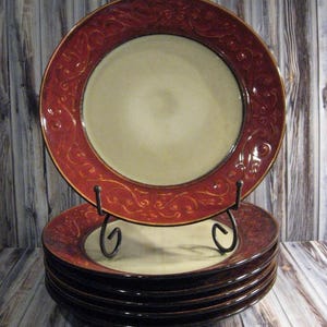 May include: Set of six dinner plates with a red and cream floral design. The plates are stacked on a metal stand.