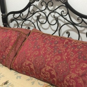 May include: Two red patterned pillows with gold trim on a black metal bed frame.