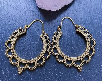 May include: A pair of gold hoop earrings with a delicate, intricate design. The earrings are made of metal and have a circular shape with a small, dangling bead at the bottom.