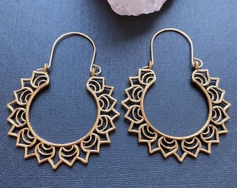 May include: A pair of gold-toned hoop earrings with a delicate, intricate design. The earrings are made of metal and have a circular shape with a floral pattern.