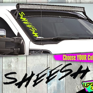 May include: A black and white graphic of the word "SHEESH" in a stylized font. The word is written in a bold, brush-stroke style. The image is set against a woodgrain background. The text "Choose YOUR Color!" is in pink letters on a white background. The text "UPRISE Offroad" is in a white box with a pink outline. The text is in a black box with a white outline.