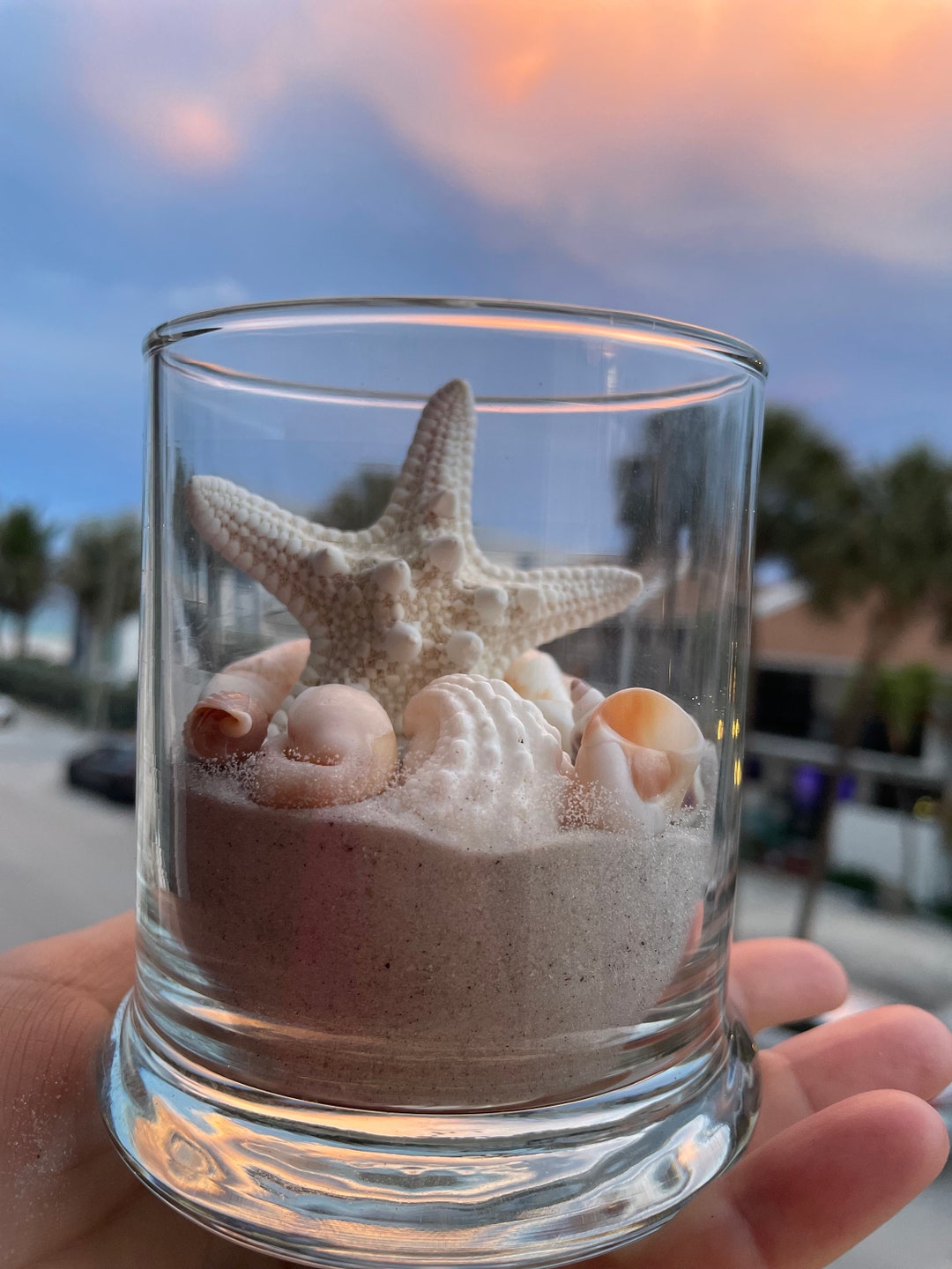 Vaso in vetro con sabbia e conchiglie della Florida e una candela