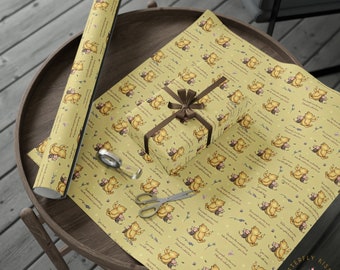May include: Yellow wrapping paper featuring a repeating pattern of a cartoon bear, flowers, and text. A wrapped gift with a brown ribbon sits on the paper, along with a roll of paper, scissors, and tape. The text reads "Sometimes the smallest things take up the most room in your heart."