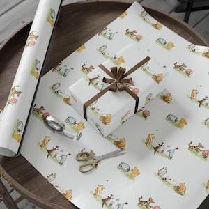 Gift wrapping setup featuring Classic Winnie the Pooh and friends patterned wrapping paper spread across a wooden round table. A wrapped present with a brown ribbon sits in the center, surrounded by scissors, tape, and rolled wrapping paper. The design shows Pooh, Piglet, Tigger, and Eeyore in watercolor-style illustrations on white paper.