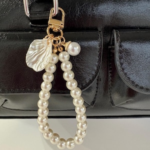 Pingente elegante com pérolas | Chaveiro com fecho dourado e detalhes em concha e pérola | Acessórios charmosos para chaves, AirPods e celular