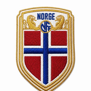 Może przedstawiać: Wyszywana naszywka w kształcie tarczy z norweską flagą w kolorach czerwonym, białym i niebieskim. Wz&oacute;r zawiera niebieski napis NORGE, okrągłe logo NFF oraz dwie złote figurki lw&oacute;w po bokach tekstu, całość wykończona złotym obszyciem.