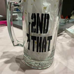 May include: A clear glass beer mug with a black vinyl decal that reads "2ND THAT." The decal features a stylized image of a rifle.
