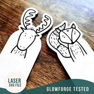May include: Two black and white laser cut wooden bookmarks, one with a deer head and the other with a fox head. The bookmarks are on a wooden surface. The text "LASER SVG FILE" and "GLOWFORGE TESTED" are visible on the image.