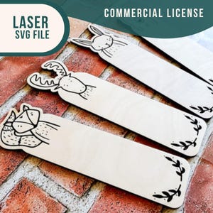 May include: Four wooden bookmarks with different animal designs. The designs include a deer, a rabbit, a fox, and a leafy design. The bookmarks are on a brick background.  COMMERCIAL LICENSE