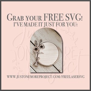 Op de afbeelding: Een houten cirkel met een bloemmotief, inclusief zonnebloemen en lavendel, is klaar om te worden gepersonaliseerd. De tekst "GRAB YOUR FREE SVG! I'VE MADE IT JUST FOR YOU!" wordt boven de cirkel weergegeven. Het websiteadres "WWW.JUSTONEMOREPROJECT.COM/FREELASERSVG" wordt onder de cirkel weergegeven.