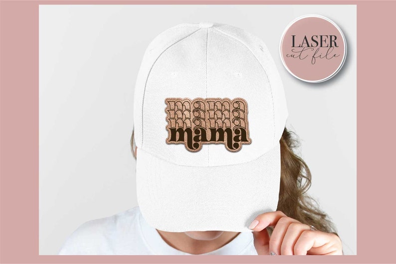 K&ouml;nnte beinhalten: Wei&szlig;e Baseballkappe mit einem braunen und schwarzen "mama"-Patch auf der Vorderseite. Der Patch hat einen Retro-Schriftart-Stil.
