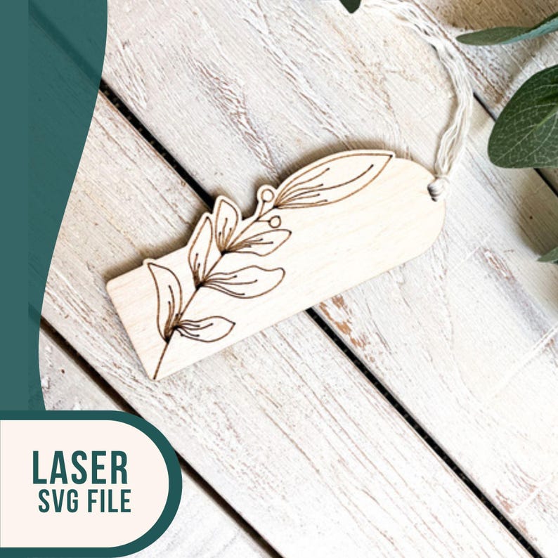 May include: A wooden bookmark with a laser-cut design of a leafy branch. The bookmark has a hole at the top for a string or ribbon.