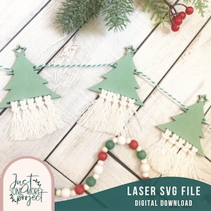 May include: A green wooden Christmas tree garland with white fringe, strung with white and green twine. The garland is on a white wood background. The text "LASER SVG FILE DIGITAL DOWNLOAD" is at the bottom of the image.