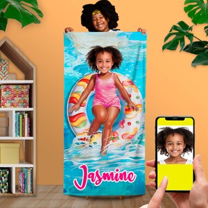 May include: A blue beach towel with a colorful candy-themed inner tube and a girl in a pink swimsuit floating on it. The towel has the name "Jasmine" written in pink letters.