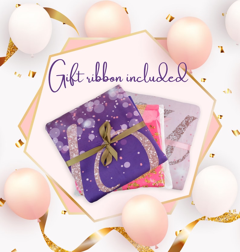 May include: A gift-wrapped set of three purple, pink, and white blankets with glitter accents. The blankets are tied with a brown ribbon and the text "Gift ribbon included" is written in purple on a pink background.