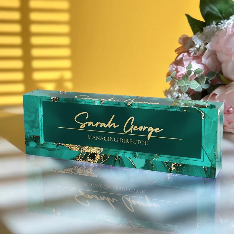 May include: A green and gold acrylic desk nameplate with the text "Sarah George, Managing Director".