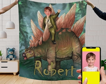 May include: A personalised green, brown and red dinosaur blanket with a boy riding on top. The blanket has the name "Robert" written in gold lettering.