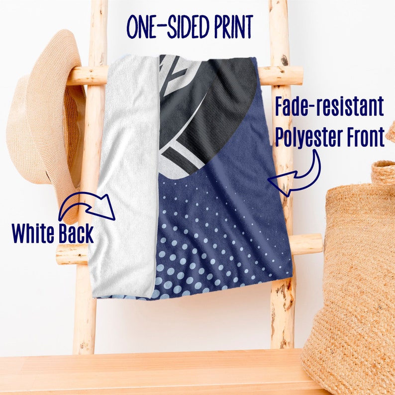 May include: A beach towel with a one-sided print. The front features a navy blue design with white dots and a black and white graphic. The back is white. The towel is made of fade-resistant polyester.