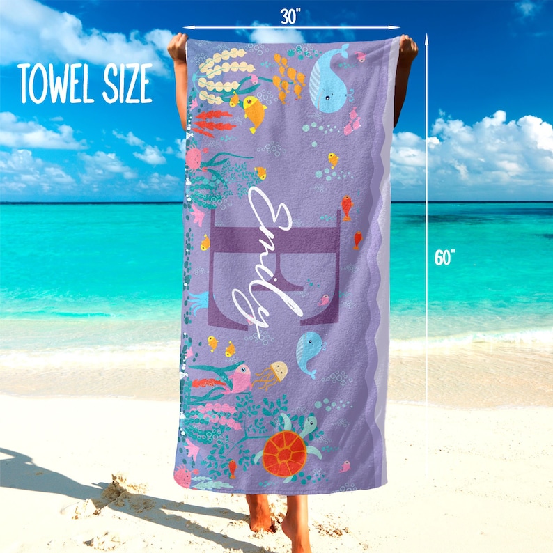 May include: A purple beach towel with a sea life design. The towel features a large letter "E" with the name "Emily" written in white. The towel is 30 inches by 60 inches.