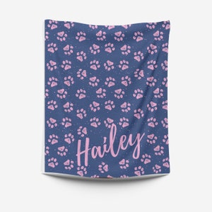 May include: A blue blanket with a pink paw print pattern and the name "Hailey" written in pink.