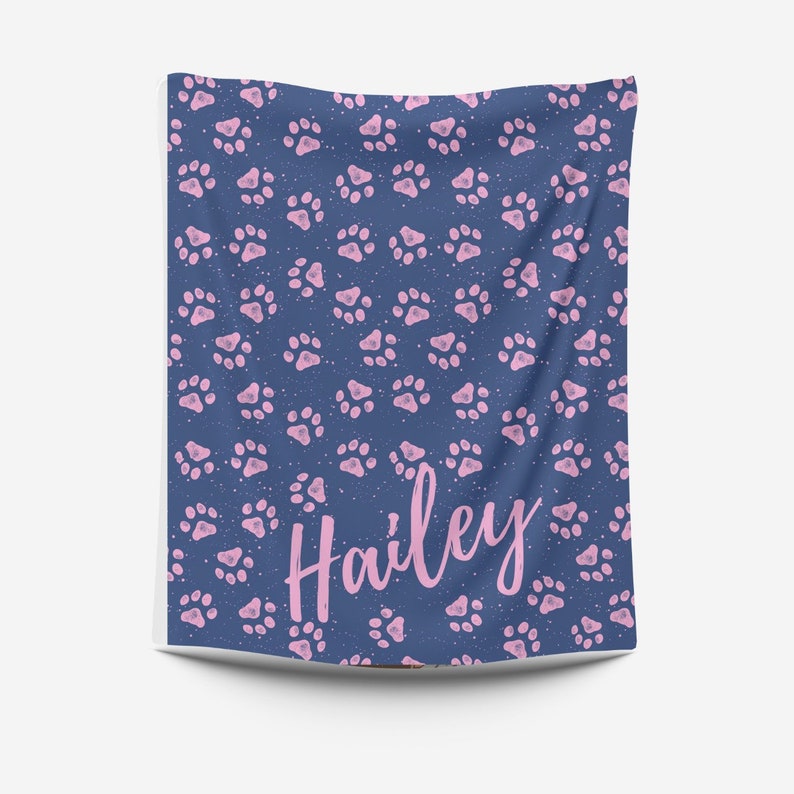 May include: A blue blanket with a pink paw print pattern and the name "Hailey" written in pink.
