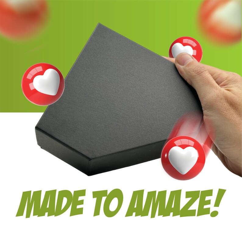 May include: A black box with a triangular shape is being lifted by a hand. Three red heart-shaped buttons with white hearts inside are floating around the box. The text "MADE TO AMAZE!" is written in green letters below the box.
