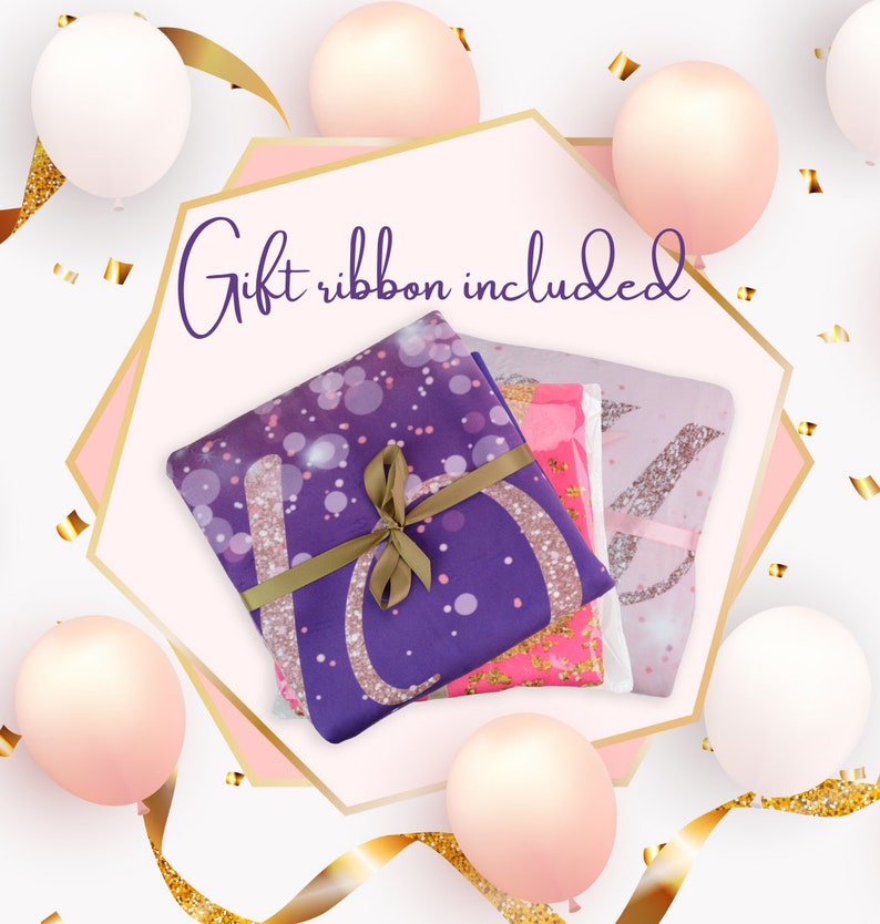 May include: A gift-wrapped set of three purple, pink, and white blankets with gold glitter accents. The blankets are tied with a brown ribbon and the text "Gift ribbon included" is written in purple on a pink background.