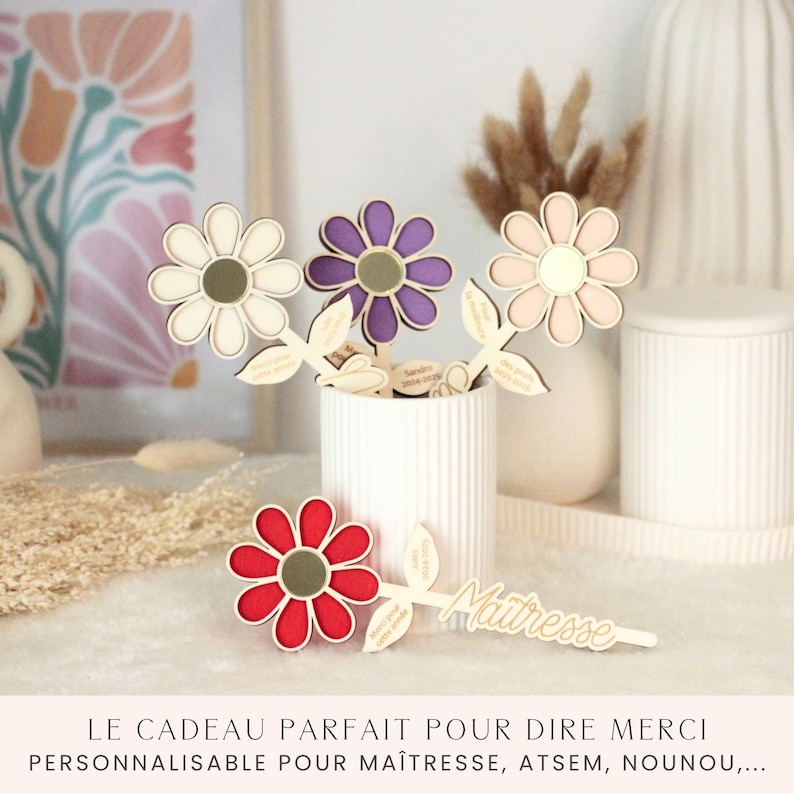May include: Wooden flower decorations in white, purple, pink, and red with green leaves. The flowers are in a white vase. The word "Mattresse" is written on a wooden leaf. The text at the bottom says "LE CADEAU PARFAIT POUR DIRE MERCI PERSONNALISABLE POUR MA&Icirc;TRESSE, ATSEM, NOUNOU,..."