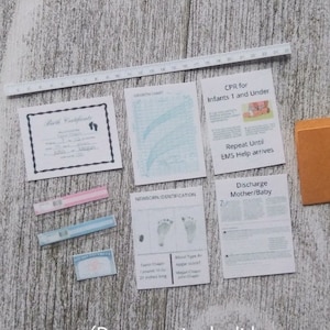 May include: A collection of documents related to a new baby, including a birth certificate, a growth chart, a newborn identification form, a CPR instruction sheet for infants, a discharge form for mother and baby, and a folder. The documents are on a light wood surface.