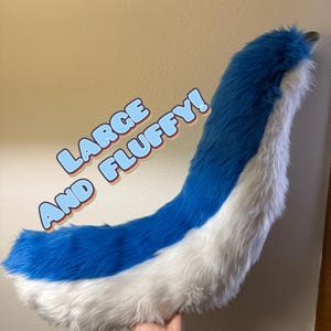 May include: A large, fluffy, curved tail made of long-pile faux fur. The top side of the tail is a vibrant blue, while the underside is white. The text "LARGE AND FLUFFY!" is overlaid on the image in blue letters with a white and orange outline.