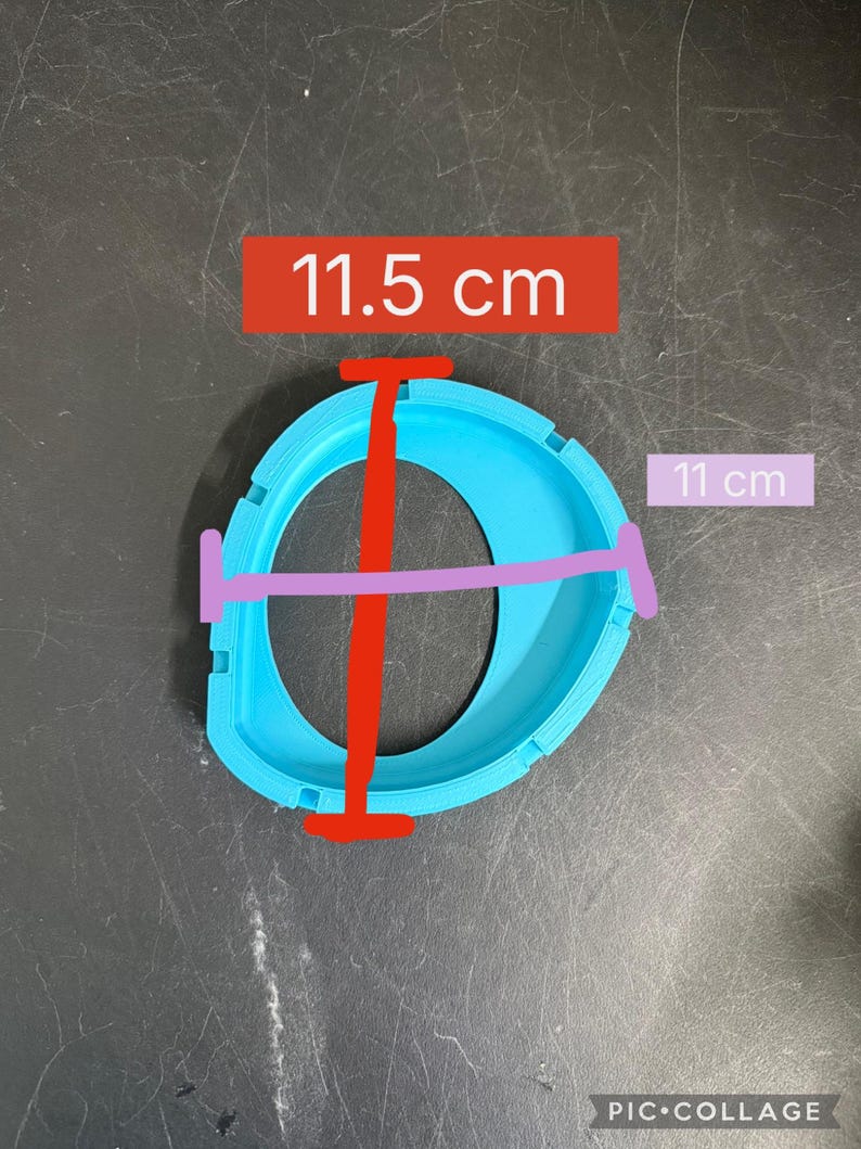 K&ouml;nnte beinhalten: Ein hellblauer, kreisf&ouml;rmiger, 3D-gedruckter Kunststoffrahmen mit einer zentralen &Ouml;ffnung. Das Objekt weist ein vertikales Ma&szlig; von 11,5 cm und ein horizontales Ma&szlig; von 11 cm auf, wie durch die roten und violetten Linien im Bild dargestellt.