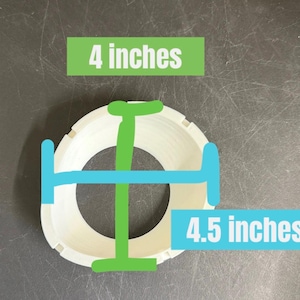 Pode incluir: Um objeto circular branco com um exterior estriado. Uma linha verde indica uma medida vertical de 10,16 cm, enquanto uma linha azul indica uma medida horizontal de 11,43 cm, com etiquetas de texto correspondentes para cada dimens&atilde;o.