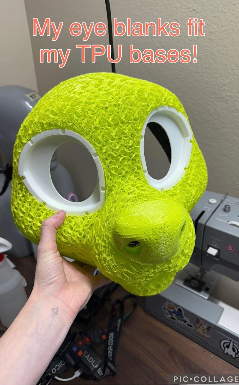 K&ouml;nnte beinhalten: Eine leuchtend neongelbe, 3D-gedruckte Tierkopfbasis mit einer texturierten, por&ouml;sen Oberfl&auml;che und zwei gro&szlig;en wei&szlig;en, kreisf&ouml;rmigen Augenh&ouml;hlen. Der Text "My eye blanks fit my TPU bases!" ist oben im Bild in Rot aufgedruckt.