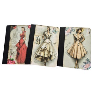 May include: Three rectangular notebooks with black spines and covers featuring fashion illustrations. The left shows a person in a red gown, the center a person in a white dress with grid lines, and the right a person in a plaid dress with floral accents.