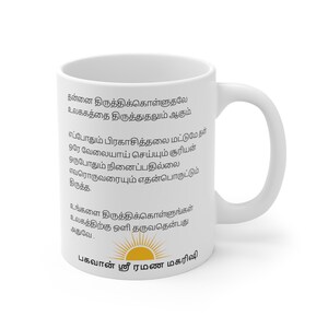 May include: White ceramic mug with a curved handle. The mug features black text in a foreign language and a graphic of a sun. The mug is designed for hot beverages.