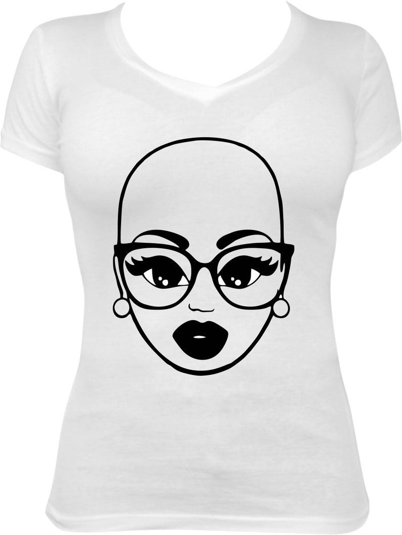 May include: White V-neck t-shirt featuring a black and white graphic of a bald woman's face wearing glasses and earrings. The graphic has large eyes, thick-rimmed glasses, and full lips. The design is simple and bold.