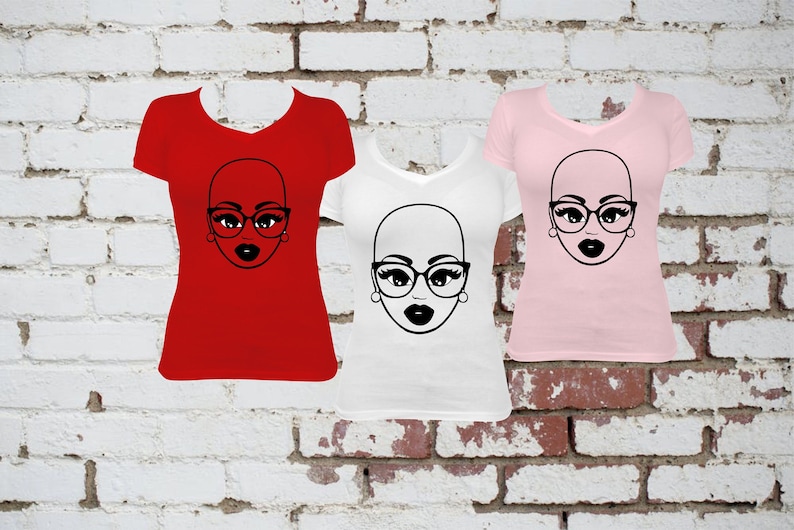 May include: Three v-neck t-shirts in red, white, and pink, each featuring a black graphic of a bald face wearing glasses and lipstick. The shirts are displayed against a brick wall background.
