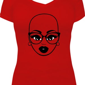 May include: A red V-neck t-shirt featuring a black and white graphic of a bald woman's face wearing glasses and earrings. The woman's lips are black. The graphic is centered on the front of the shirt.