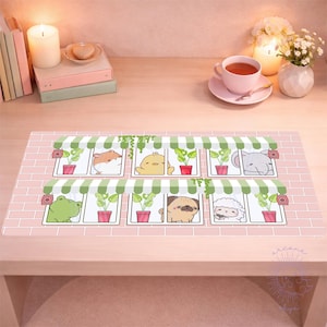 May include: A rectangular desk mat featuring a pink brick wall design with cartoon animals in windows. The animals include a hamster, chick, elephant, frog, pug, and sheep. Each window has a green awning and a potted plant.