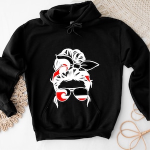 Pode incluir: Moletom preto com um gráfico branco de uma mulher com óculos de sol, bandana e coque. Os óculos de sol e a bandana têm detalhes em vermelho e preto. O moletom tem capuz com cordão e um bolso frontal.