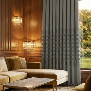 Peut inclure: Un salon luxueux avec un rideau gris au motif texturé, un canapé d'angle beige et une table basse en marbre. La pièce est éclairée par des appliques murales et un lampadaire, créant une atmosphère chaleureuse. Les murs sont lambrissés de bois foncé.