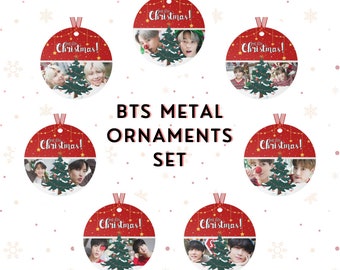 Op de afbeelding: Set van zeven rode en groene metalen kerstversieringen met afbeeldingen van de K-pop-groep BTS. Elke versiering heeft de tekst "Merry Christmas!" en een andere afbeelding van de bandleden.