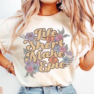 May include: A white t-shirt with a floral design and the text "Life is Short Make it Epic" in yellow and orange letters.