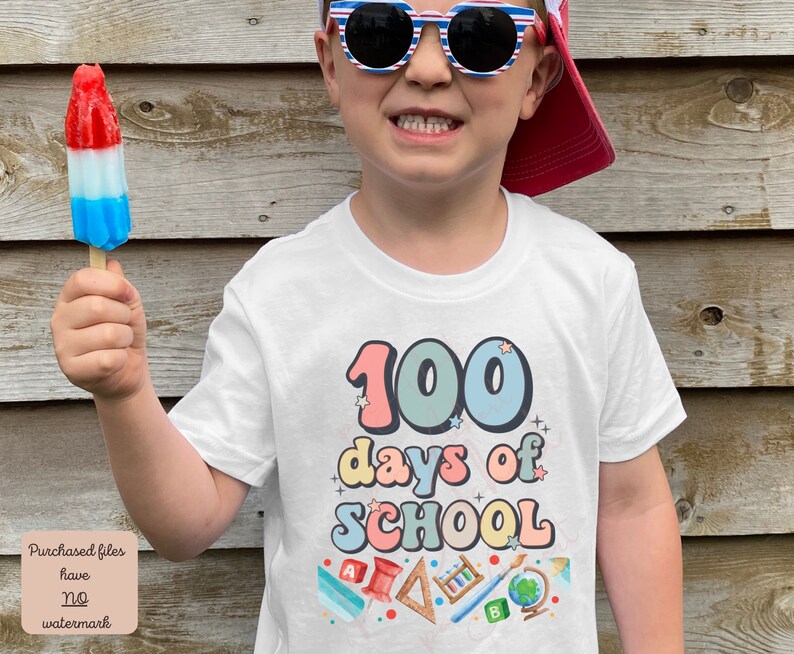 K&ouml;nnte beinhalten: Ein wei&szlig;es T-Shirt mit dem Text "100 Tage Schule" in bunten, Retro-Lettern. Das Shirt zeigt verschiedene schulthemenbezogene Illustrationen, darunter einen Bleistift, einen Pinsel, einen Globus und ein Lineal.