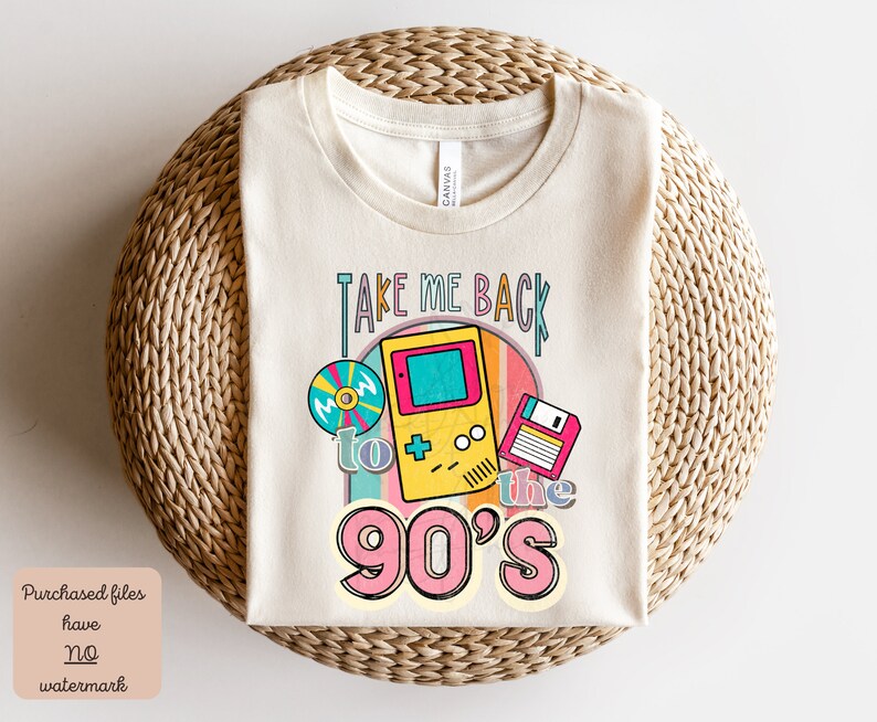 K&ouml;nnte beinhalten: Ein beiges T-Shirt mit dem Text "Take Me Back to the 90's" in einem Regenbogenbogen. Das Design beinhaltet eine Retro-Videospielkonsole, eine Diskette und eine CD.