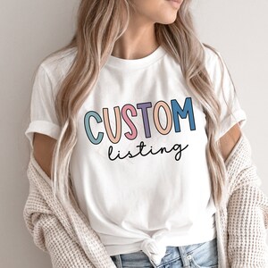 May include: White t-shirt with the text "CUSTOM listing" in colorful letters. The letters are outlined in black and have a slight 3D effect.