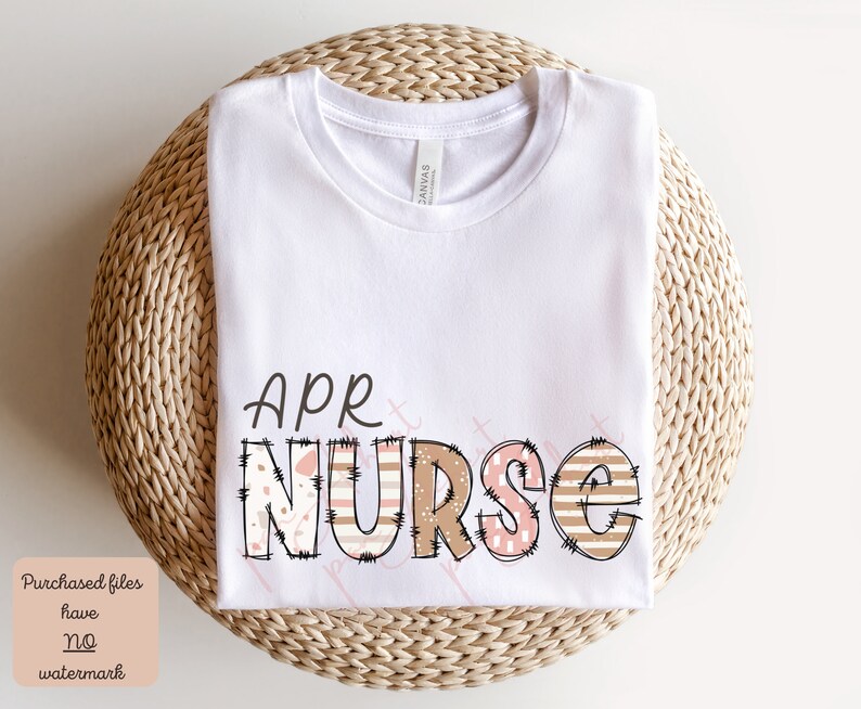 May include: White t-shirt featuring the text "APR NURSE" in brown, pink and white patterned letters. The letters have a stitched appearance.