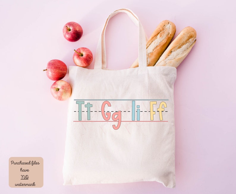 Pu&ograve; includere: Una borsa di tela bianca con le lettere "Tt Gg Ii Ff" scritte a mano in colori. La borsa &egrave; circondata da mele rosse e due pagnotte di pane.